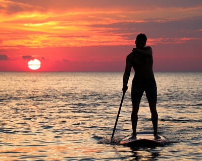 人骑在黄金小时paddleboard轮廓
